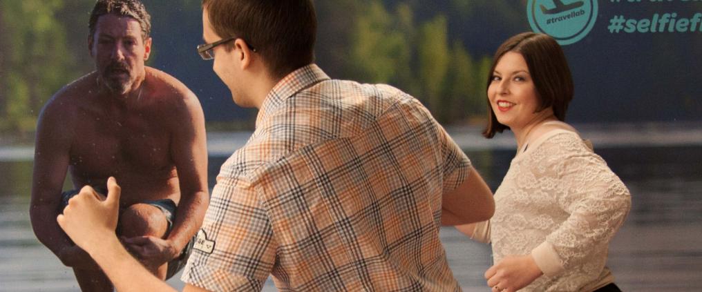 A man and a woman in front of a big poster.