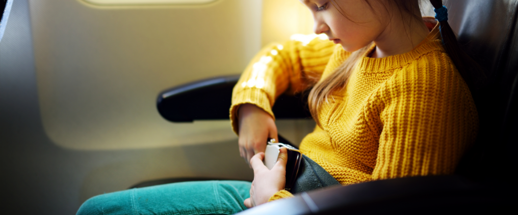 Child is sitting calmly with seat belt on in an airplane.