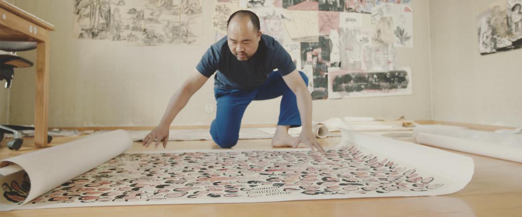 Pan Jianfeng levittää suurta julistetaidetta lattialle.