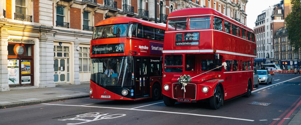 Two double decker busses stopped at street light in London.