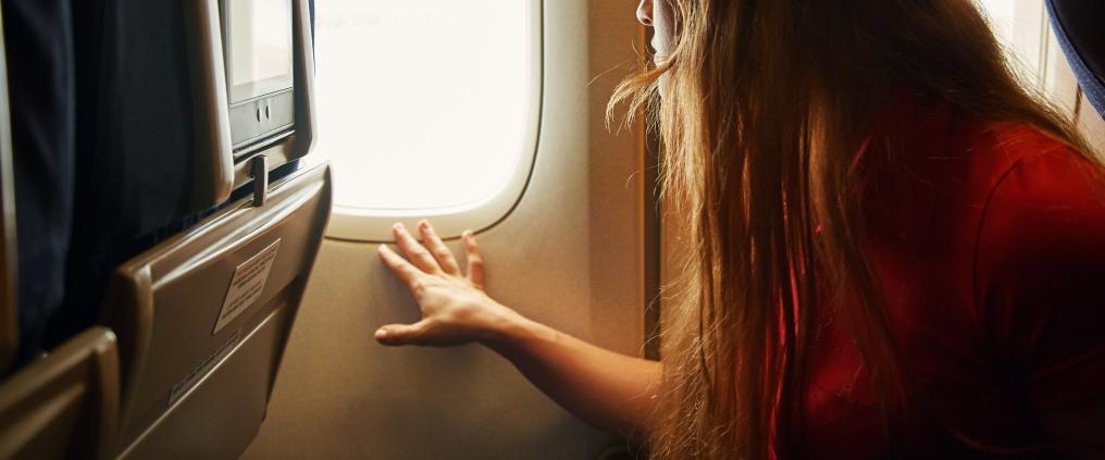 A woman looking out of airplane cabin window.
