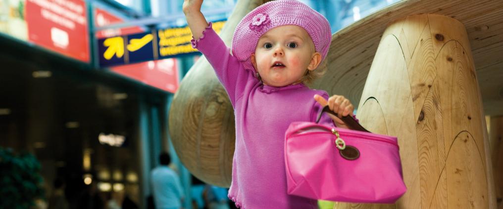 Lapsi pinkeissä vaatteissa lentokentällä.