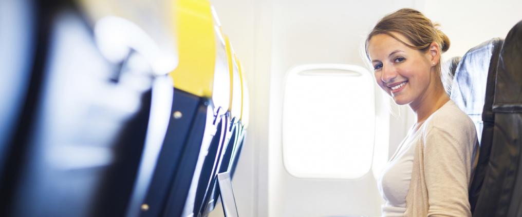Smiling woman sitting in airplane cabin seat.