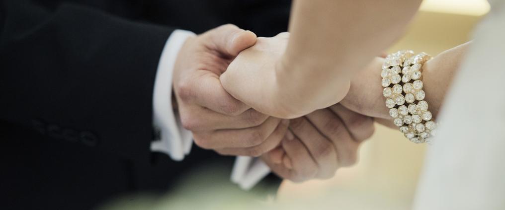 Close up of brides and grooms hand holding.