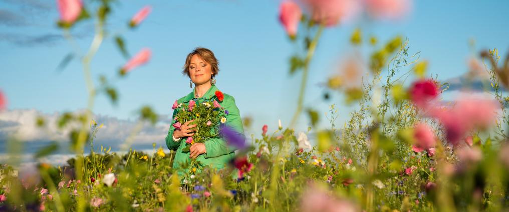 Emma Salokoski kukkaniityllä käsissään kukkakimppu.