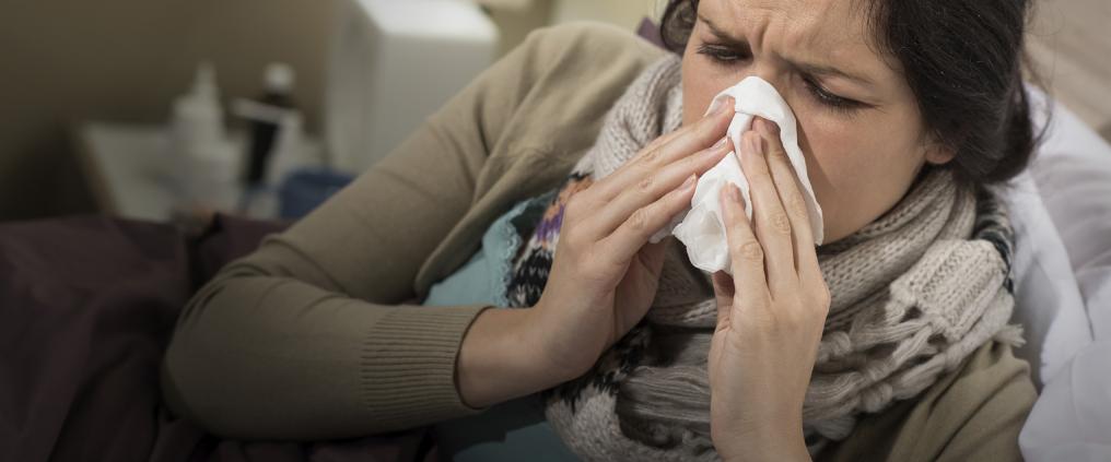 Sick woman blowing her nose into a tissue.