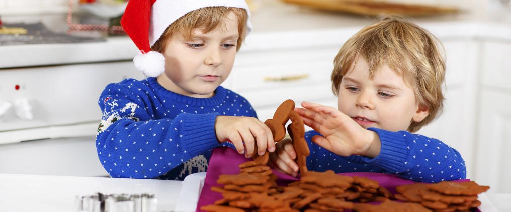 Two small children in Christmas spirit playing with gingerbread men.