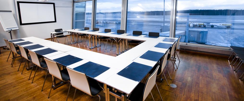 Kokoushuone, jossa pitkä pöytä ja monta tuolia.