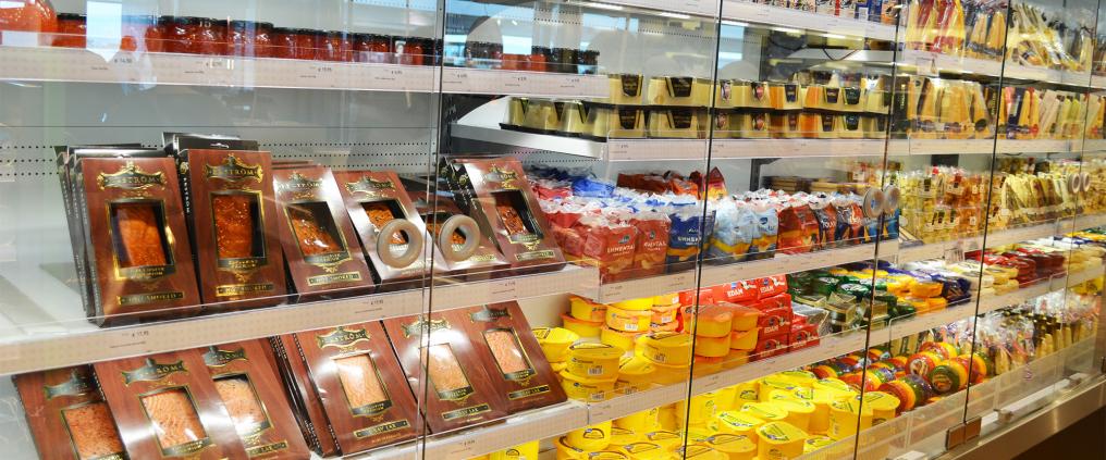 Fish fillets and cheeses in cold food display fridge.