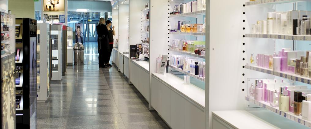 Ihmiset katselevat kosmetiikkatuotteita duty free kaupassa.