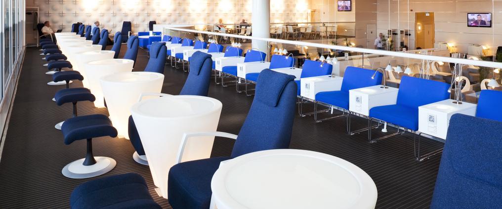 Lounge jossa on pyöreitä pöytiä ja tuoleja.