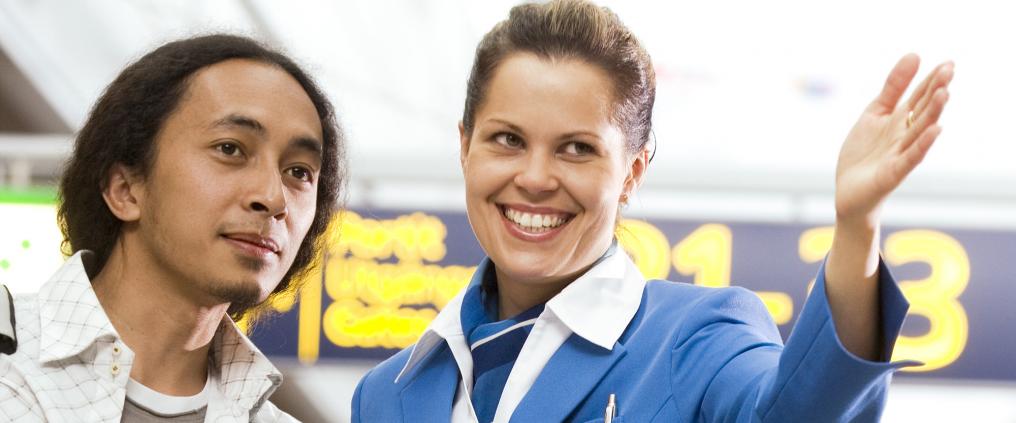 Nainen opastaa miestä lentokentällä.