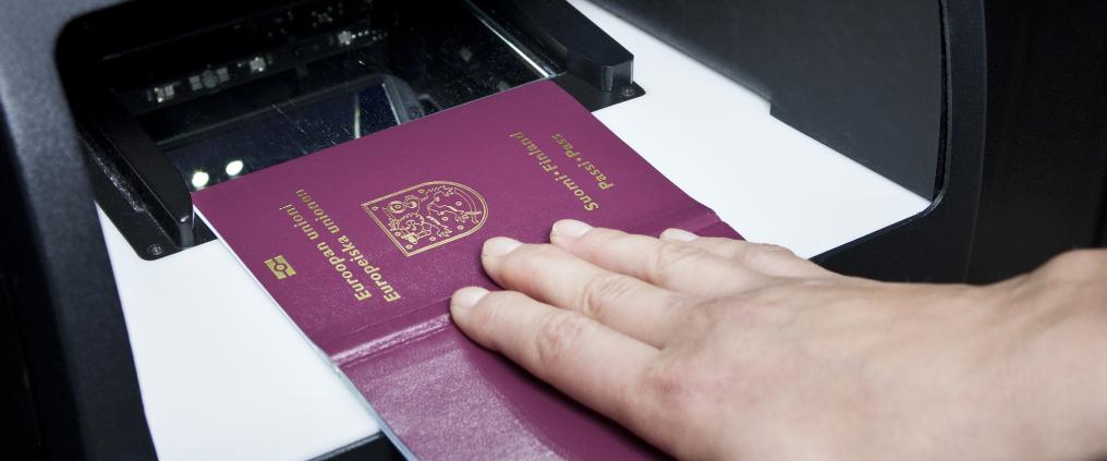 A person placing passport into a scanner.
