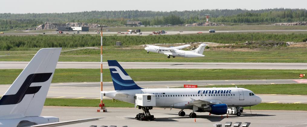 A view of Helsinki Airport runway with multiple airplanes.