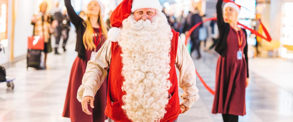 Joulupukki takanaan kaksi esiintyvää tonttua.
