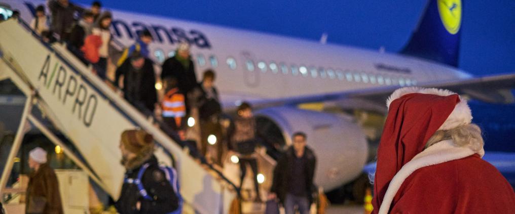 Santa watching as people are leaving a plane.