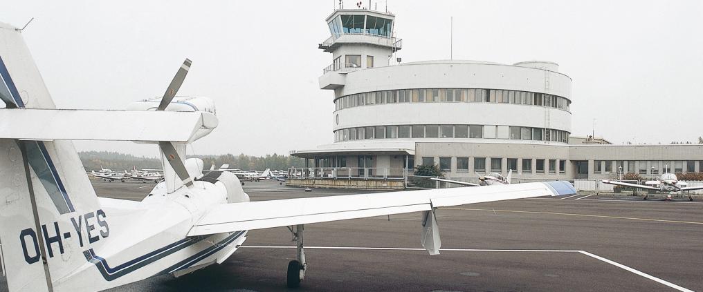 Small aircrafts and a flight control tower at Malmi airport.