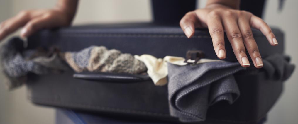 Woman packing overfilled suitcase.