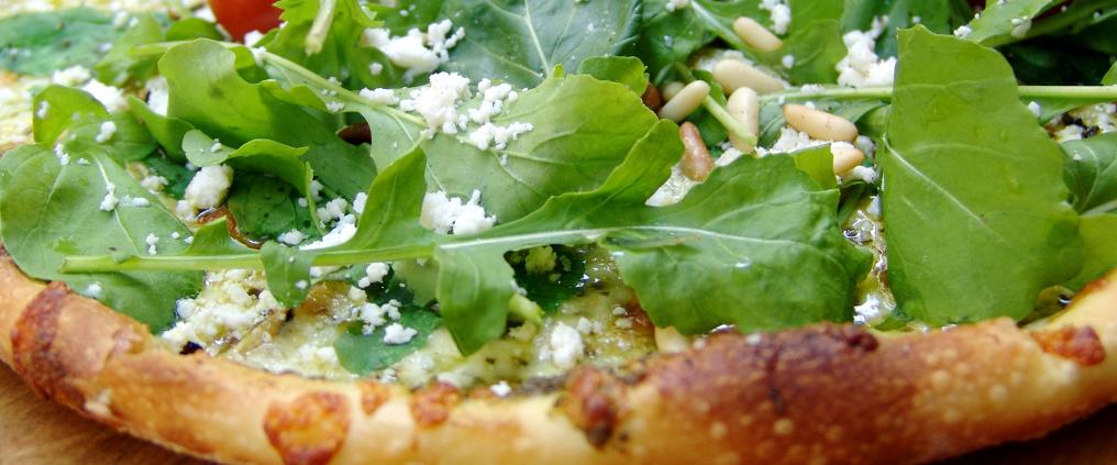 Pizza with fresh arugula and pine nuts.