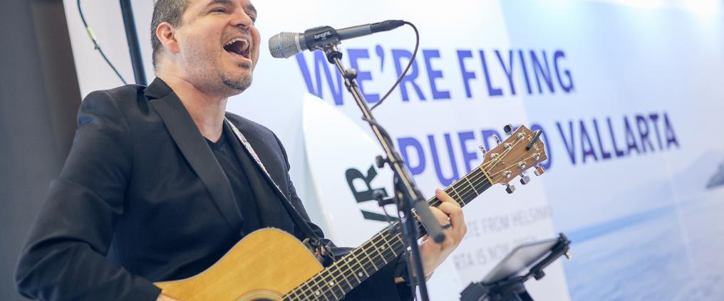 Mies soittaa kitaraa ja laulaa mikrofoniin.