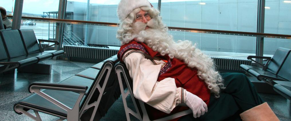 Santa Claus sitting at waiting area at airport.