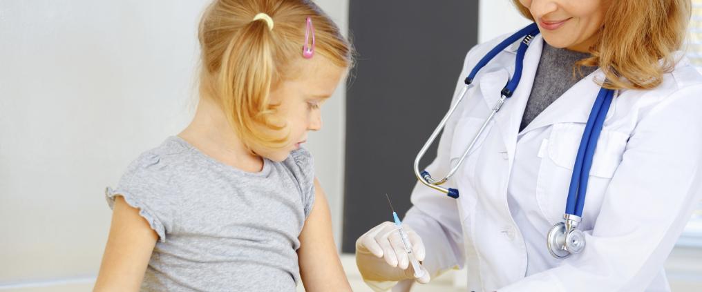 Doctor is preparing to vaccine a child using syringe.