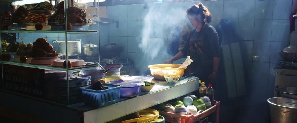 Nainen laittaa ruokaa vietnamilaisessa katuruokaravintolan keittiössä.
