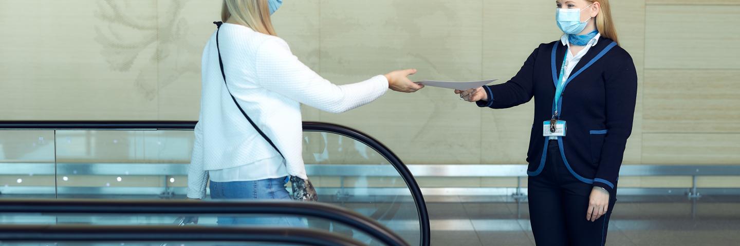 Matkustaja antaa paperin asiakasneuvojalle