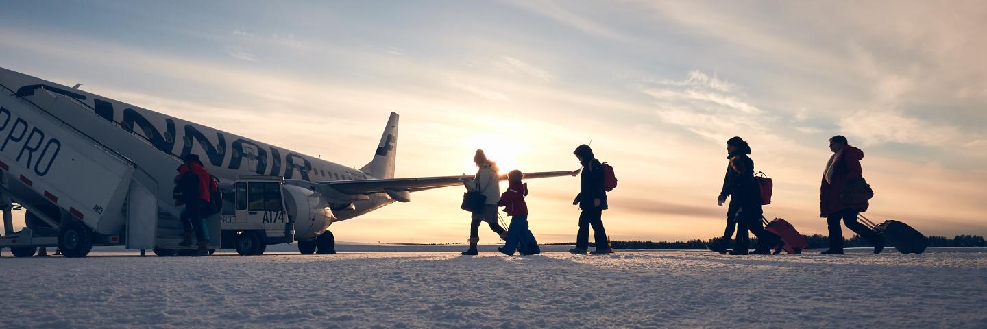 Vastavaloon otettu kuva matkustajista, jotka ovat nousemassa lentokoneeseen.