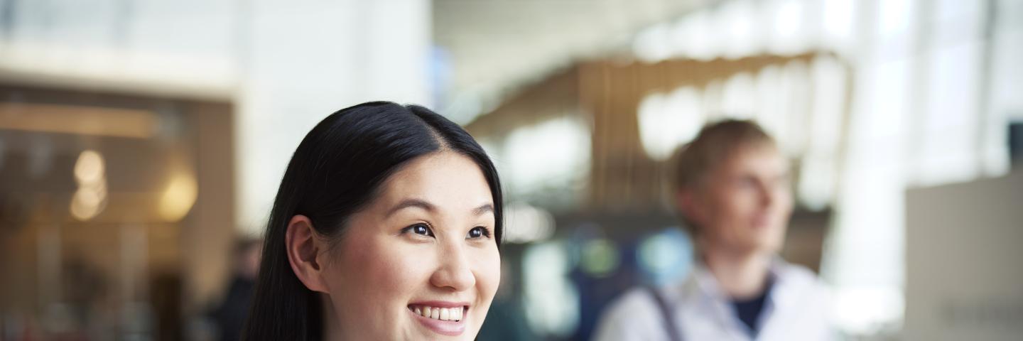 Nainen hymyilee kameran ohi lentoasemalla.