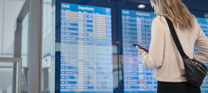 Matkustaja tarkistaa oman lentonsa ajan lentökentän aikataulunäytöltä