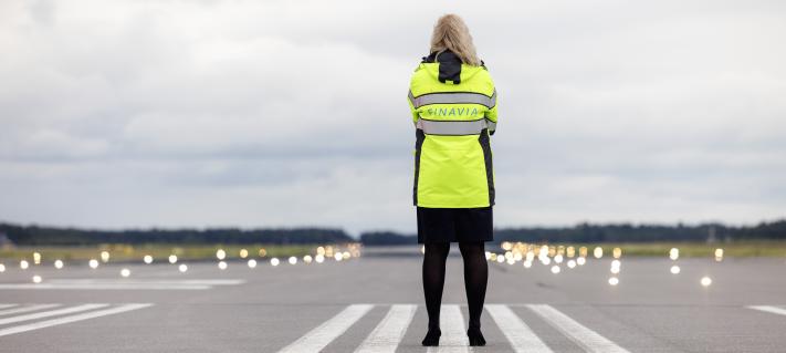 Finavian työntekijä seisoo kiitotiellä selkä kohti kameraa.